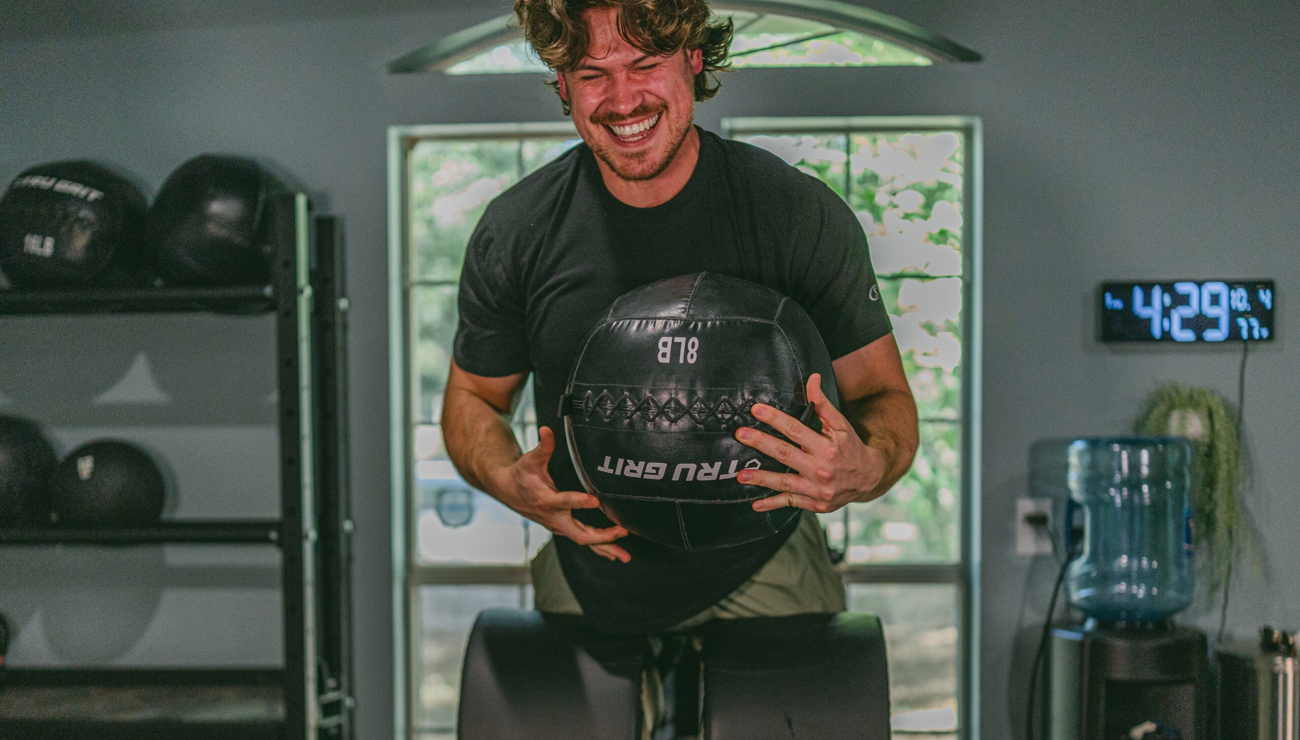 Man performing strength training with a medicine ball in a gym as part of a Gent Health men’s health and performance program